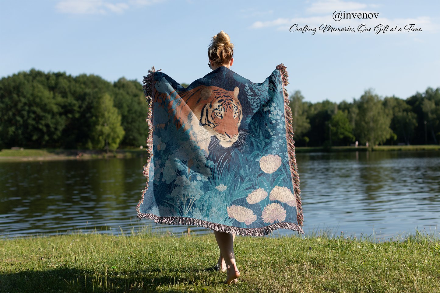 Person holding a blanket with a tiger design by a lake