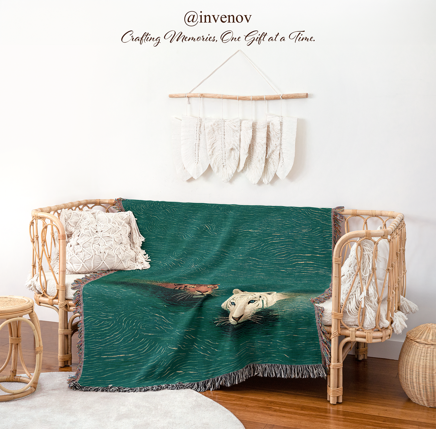 A dark teal green throw blanket with a printed illustration of a white tiger and a brown tiger, draped over a rattan daybed in a styled room setting.