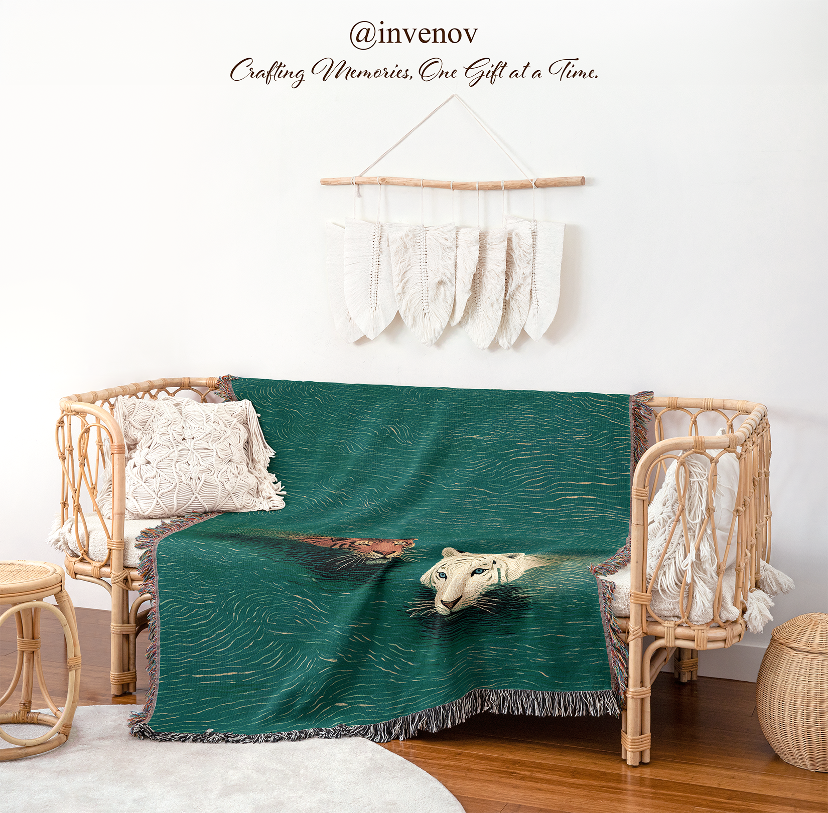 A dark teal green throw blanket with a printed illustration of a white tiger and a brown tiger, draped over a rattan daybed in a styled room setting.