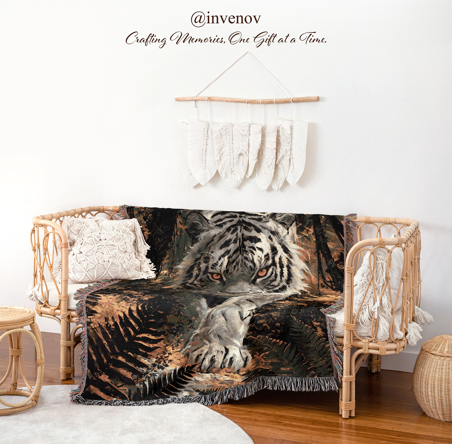 A woven rattan daybed styled in a bohemian room setting, draped with a dark brown and black throw blanket featuring a realistic tiger and leaf pattern. The daybed is decorated with white textured pillows, and the scene is styled with a wooden stool, a woven basket, and a macrame wall hanging