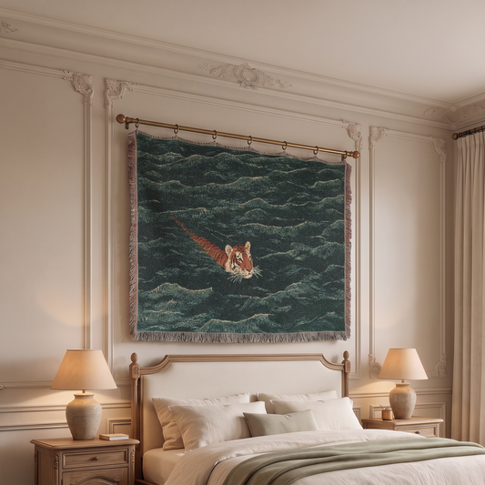 A large woven wall tapestry featuring a tiger swimming through dark teal-blue waves, hung on a gold rod above a bed in a styled bedroom.