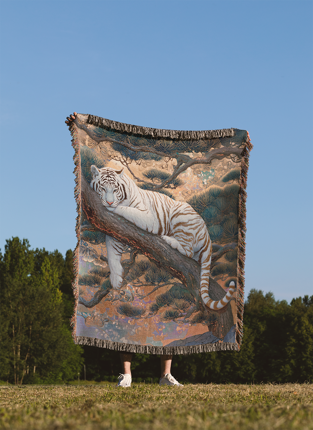 Person holding a tapestry with a white tiger design outdoors against a blue sky.