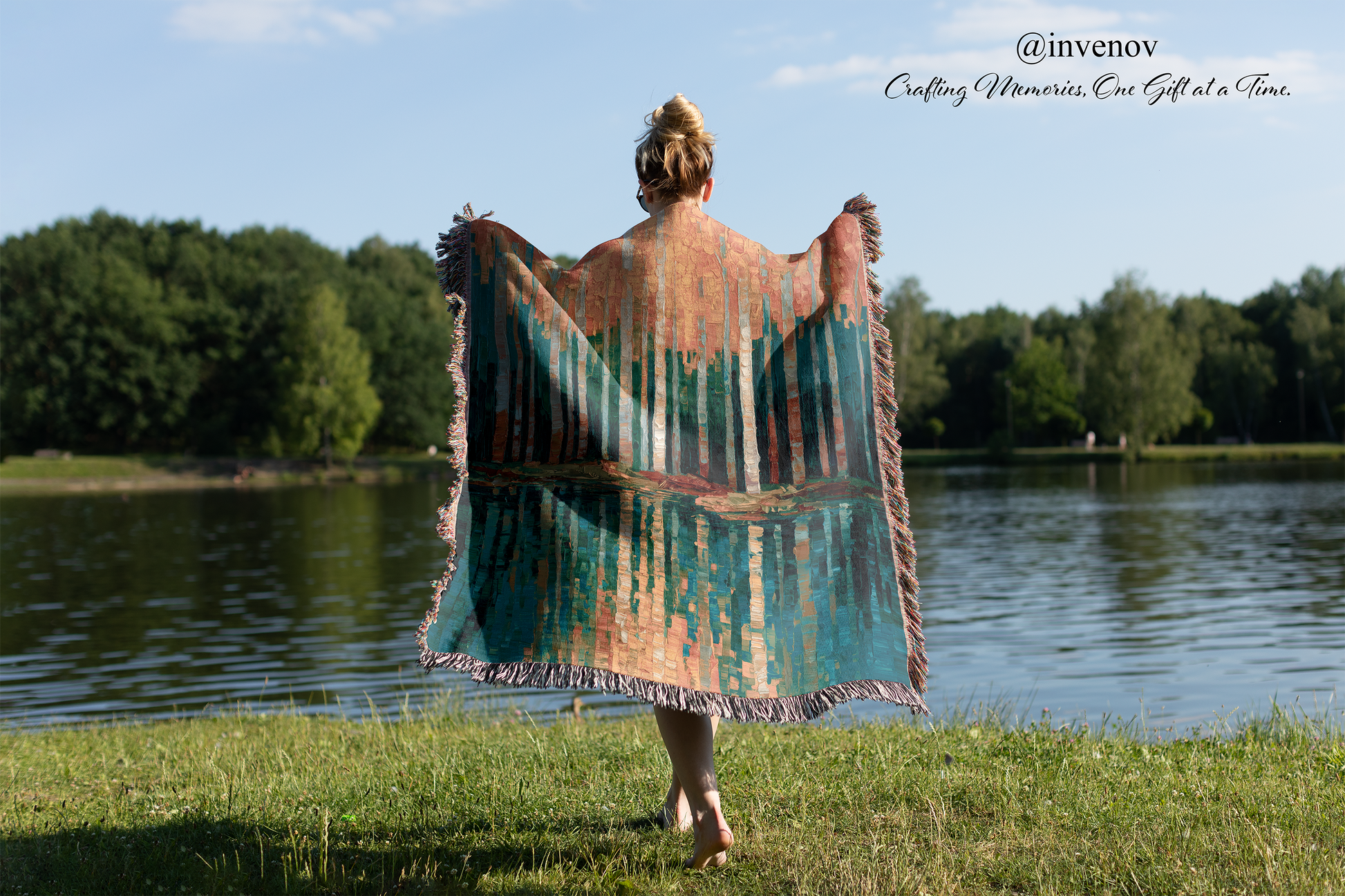 Person holding a colorful blanket by a lake with trees in the background