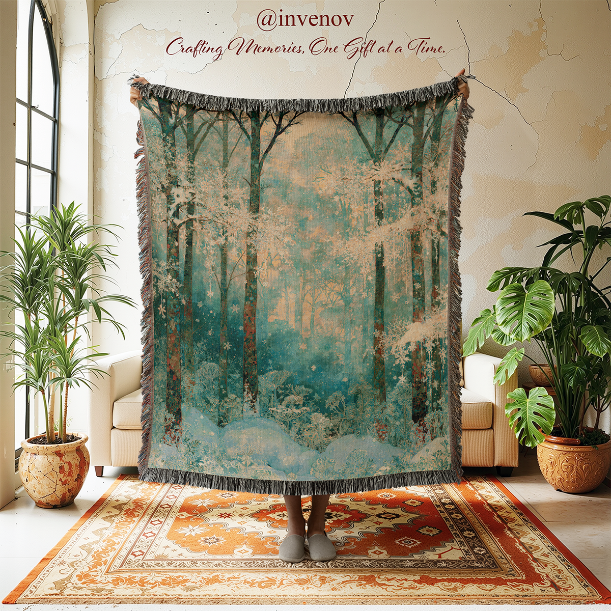 A large woven throw blanket with fringe is held up in a styled room. The blanket features a forest scene in teal, blue, brown, and beige tones.