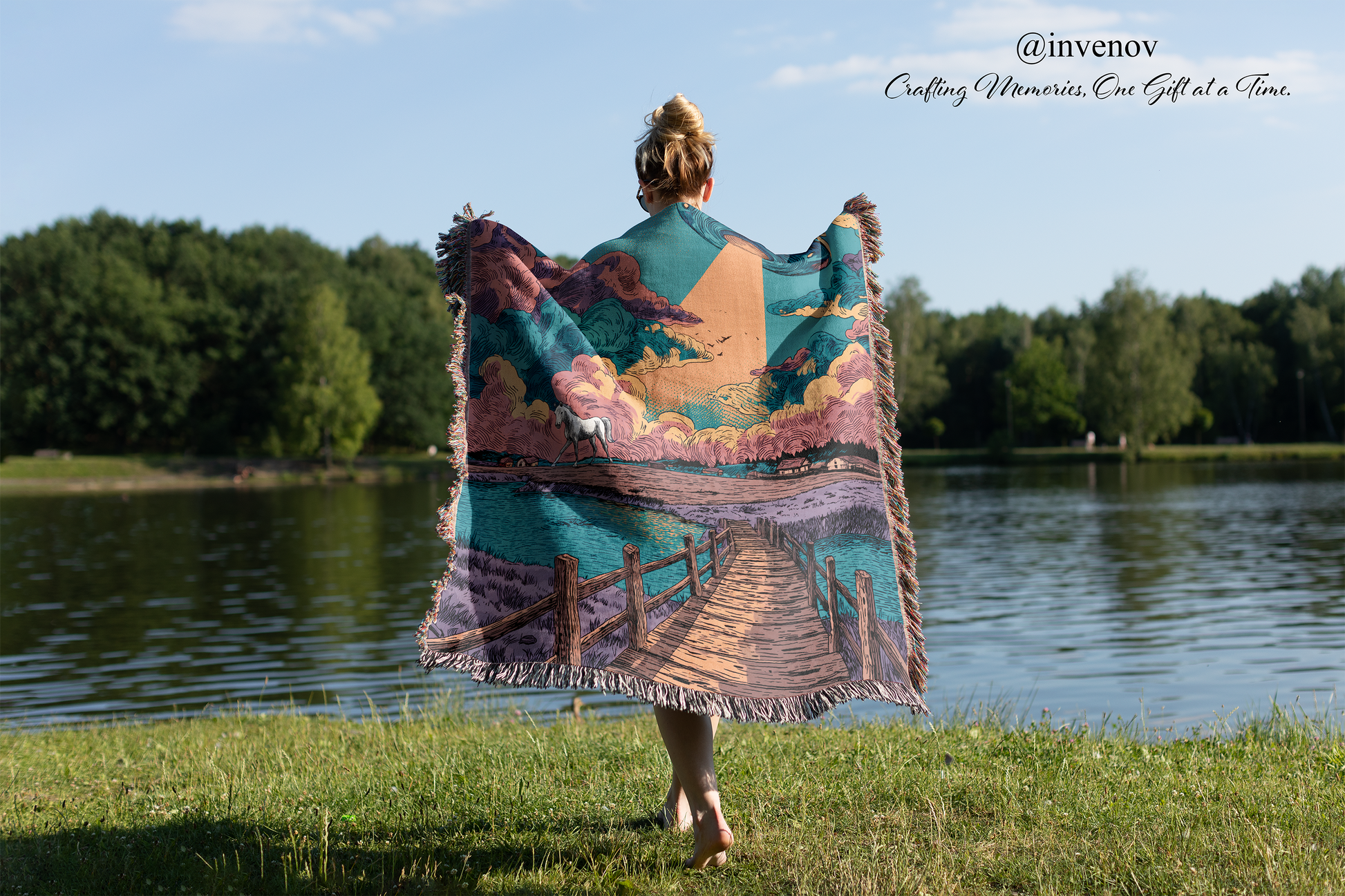 Person holding a colorful blanket with a scenic design by a lake