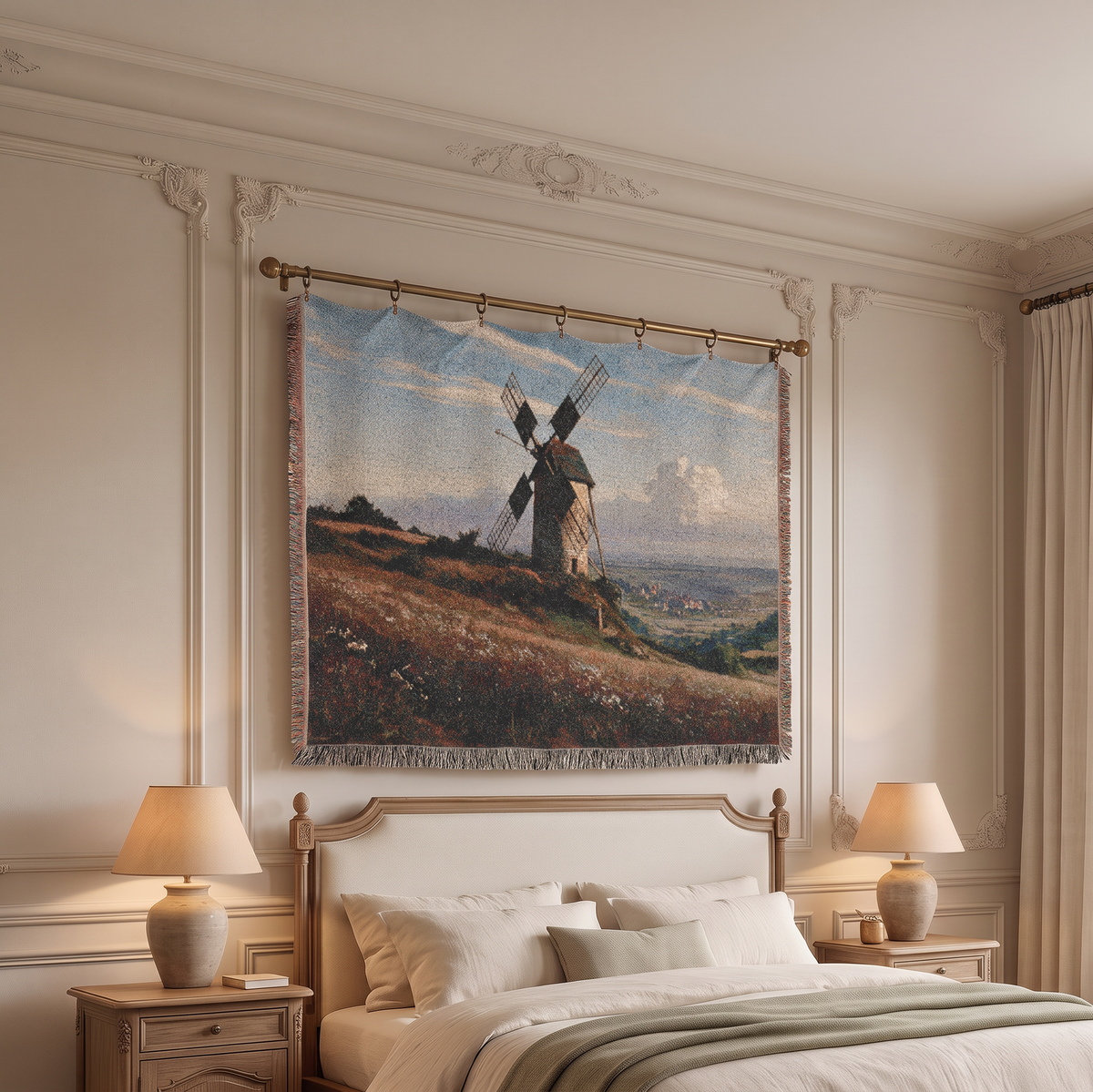 A large woven wall tapestry featuring a classic landscape painting of a windmill on a grassy hill under a blue sky, hung on a bedroom wall above a bed with two lit bedside lamps.