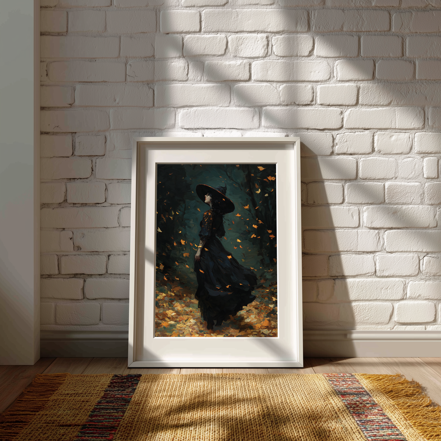 A framed art print depicting a woman in a black dress standing in a dark forest with falling leaves, leaning against a white brick wall on a woven rug.