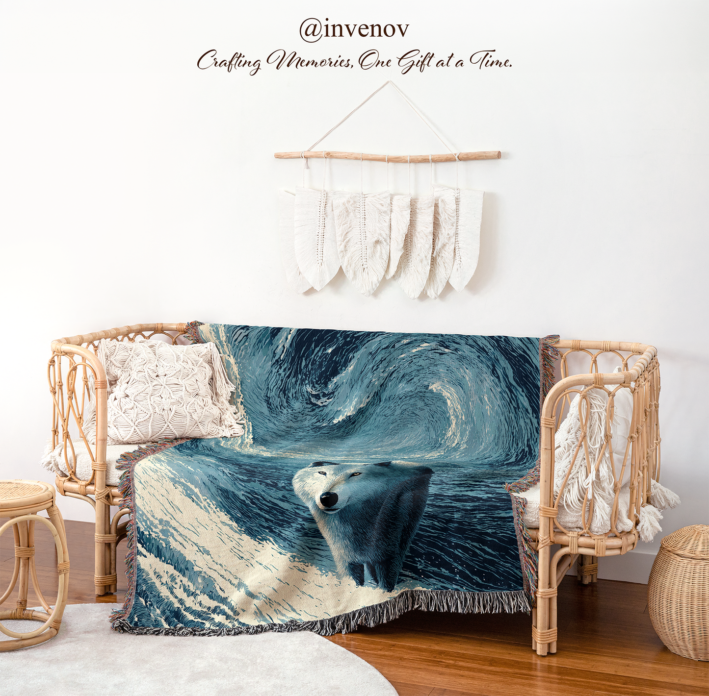 A woven throw blanket featuring a painted polar bear scene in swirling blue and white tones, draped over a rattan daybed in a styled nursery or living room setting with a white wall, hanging textile decor, wood floor, and matching rattan furniture.