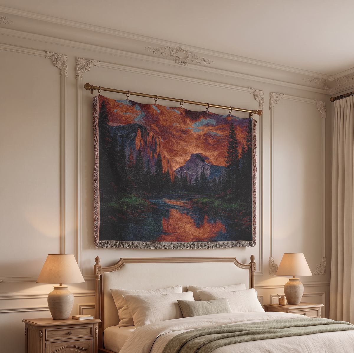 A large woven wall tapestry featuring a dramatic mountain landscape with fiery orange and red sky, dark pine trees, and a reflective lake, hanging above a bed in a classic cream-colored bedroom.